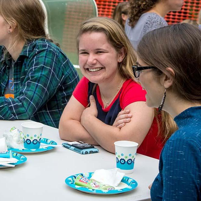 Smiling student at picnic table with friends